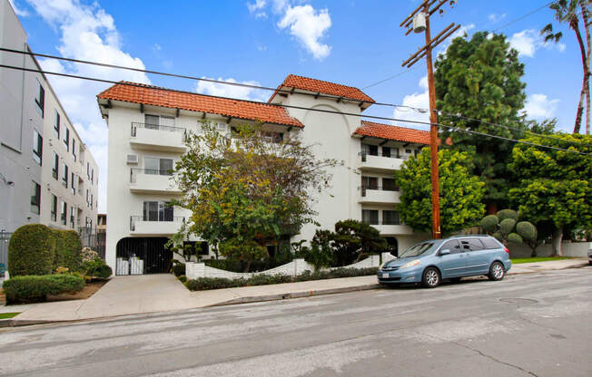 a white apartment building with a blue car parked in front