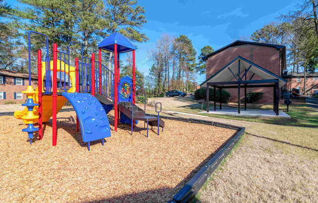 A playground with a blue and yellow slide and a red and yellow climbing frame.