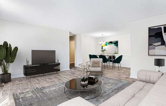 A modern living room with a grey sofa, a black television, and a glass coffee table.