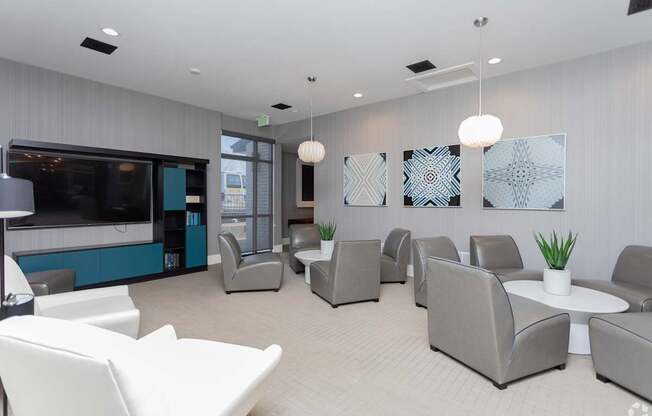 A modern waiting room with grey and white furniture and a television.