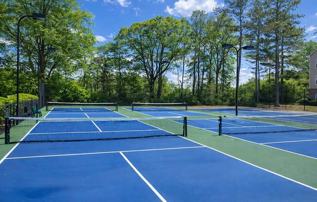 A tennis court surrounded by trees and a building in the background.