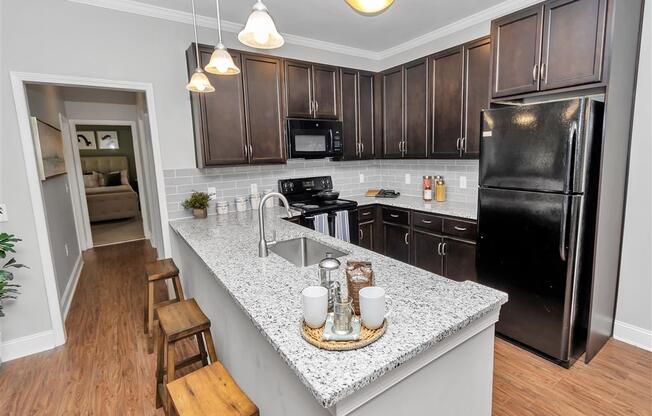 Kitchen view with pendant lights and bar seating leading into a hallway towards a bedroom
