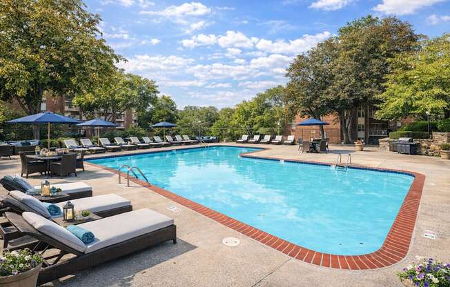 A large swimming pool surrounded by lounge chairs and umbrellas.