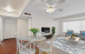 a living room with white furniture and a ceiling fan