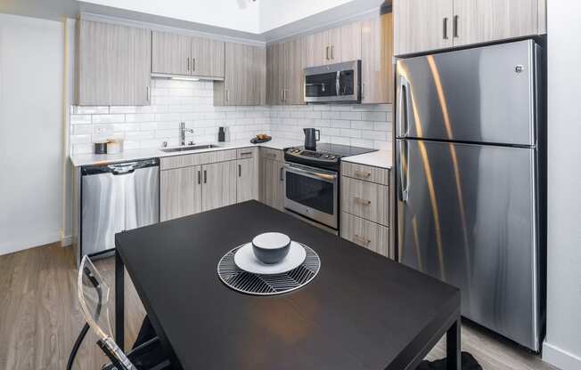 a kitchen with stainless steel appliances and a black table at OLiVE DTLA in Los Angeles, California