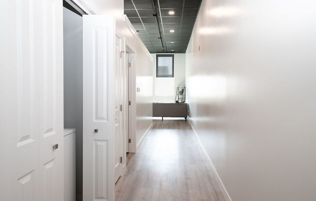 a long hallway with white walls and wood floors