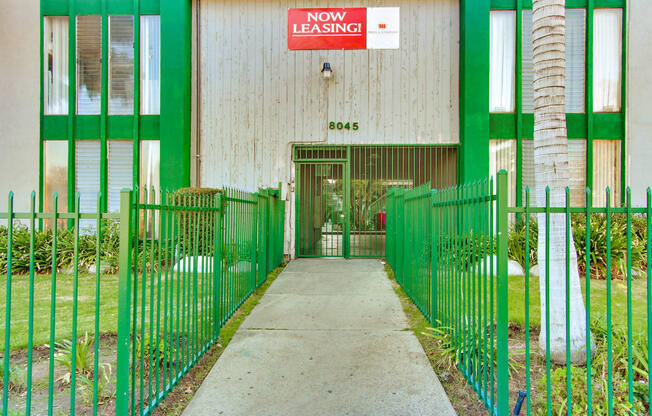 a green and white building with a sign that reads now leasing