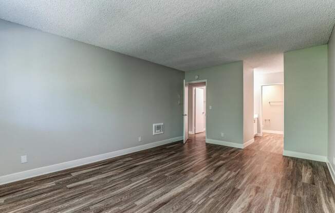 an empty living room with wood flooring and green walls at Aspire Upland Apartments, Upland, CA