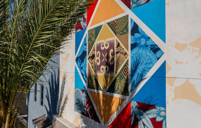 A mural on a wall with a palm tree in the foreground.