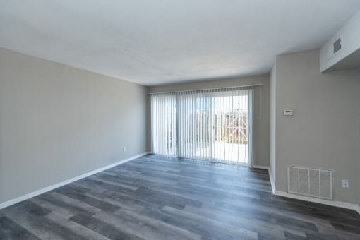 the spacious living room of an apartment with a sliding glass door