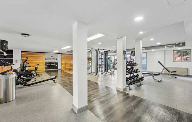 A gym with a variety of equipment including treadmills, weights, and exercise machines.