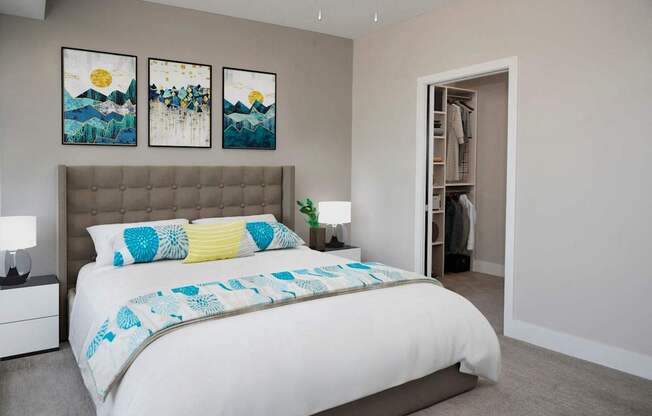 A bedroom with a large bed and two paintings on the wall.