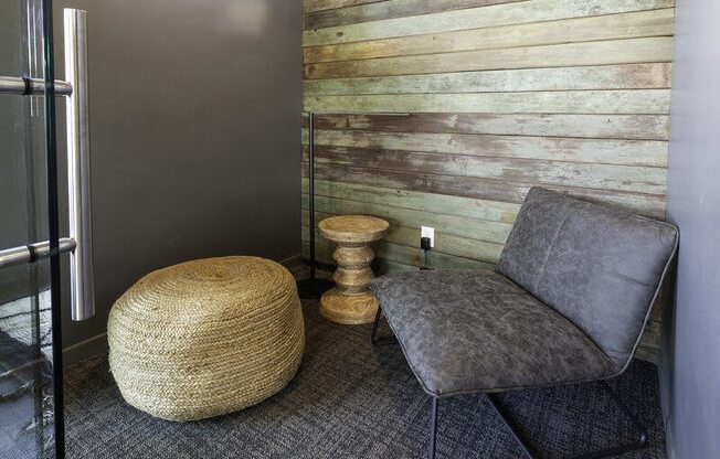 A grey chair sits in front of a wooden wall.