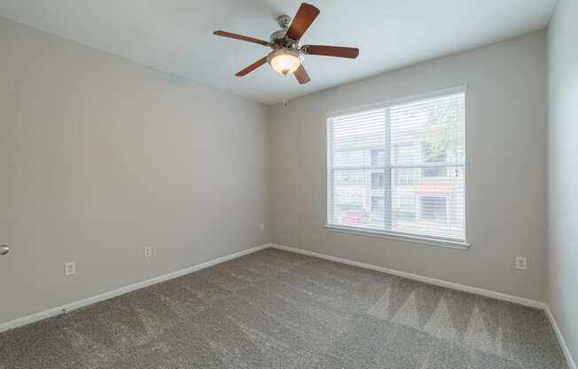 an empty room with a ceiling fan and a window