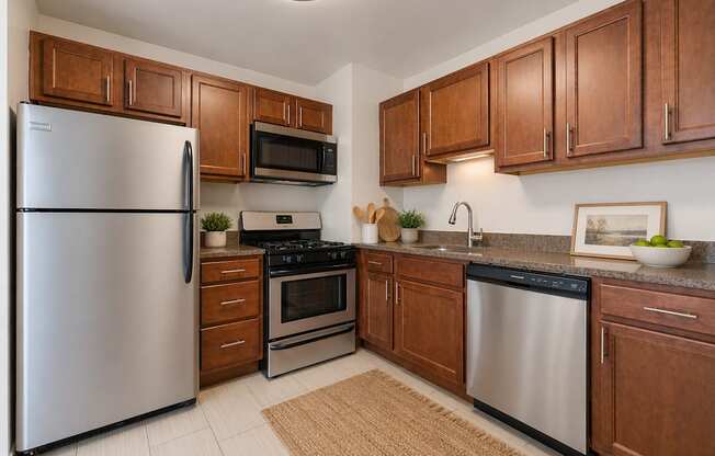 A kitchen with a refrigerator, microwave, oven, and sink.