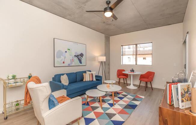 A living room with a blue couch, a white chair, and a small table.