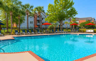 A large swimming pool surrounded by trees and chairs.