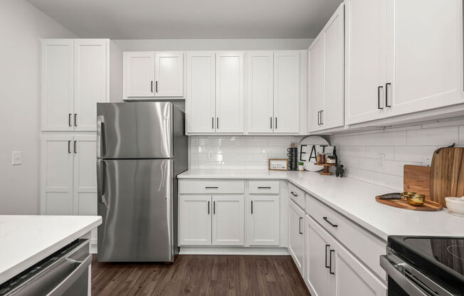 a kitchen with white cabinets and a stainless steel refrigerator