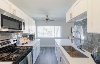 a kitchen with white cabinets and black appliances and a sink