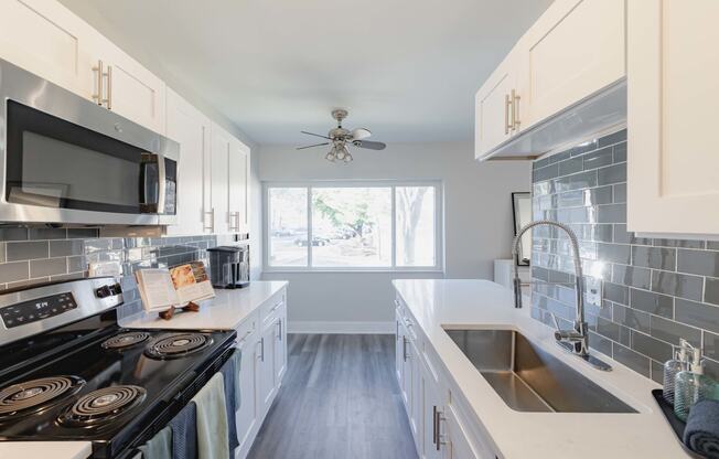 a kitchen with white cabinets and black appliances and a sink