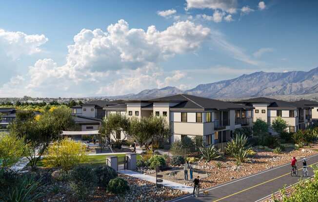 an aerial view of a row of houses with people biking on a road and mountains in the