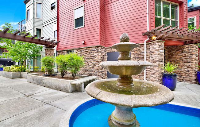 A fountain in the middle of a pool surrounded by a house.