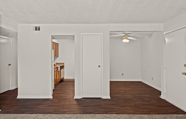 an empty living room with wood flooring and a ceiling fan