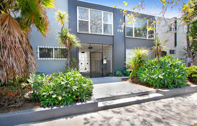 a blue house with a sidewalk and plants in front of it