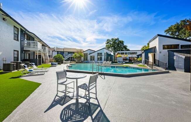 a pool with chairs and a table in front of a building