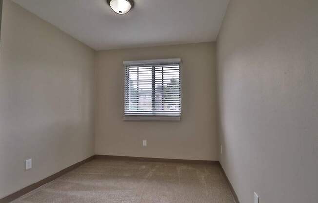 the spacious living room of an empty house with a window