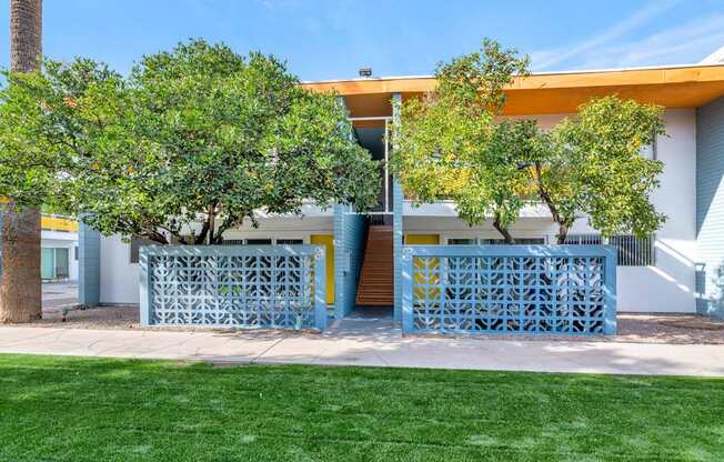 A blue and yellow building with a tree in front at The Phoenix Apartments on 6th Avenue, Arizona