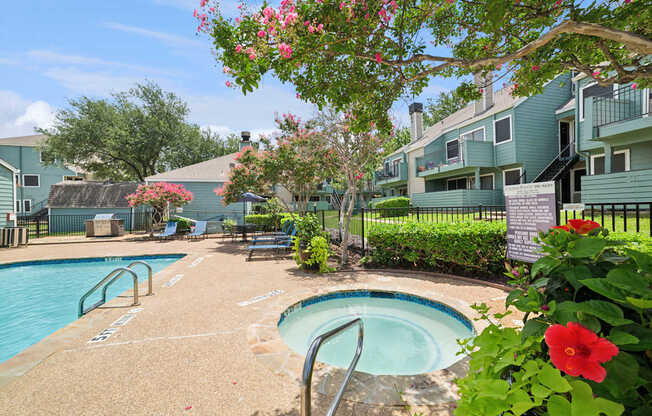 A pool surrounded by a green fence and flowers.