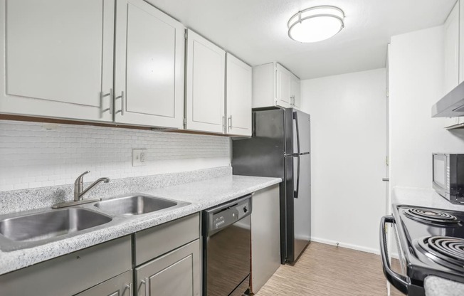 an empty kitchen with white cabinets and a stainless steel refrigerator