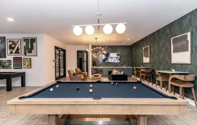 a pool table in a living room with a bar and a television
