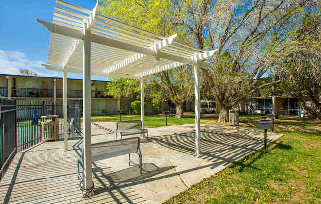 A white pergola is in the middle of a grassy area.