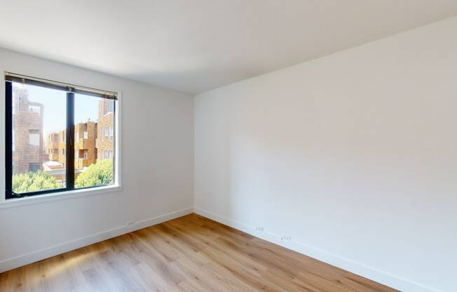 a bedroom with a large window and hardwood floors