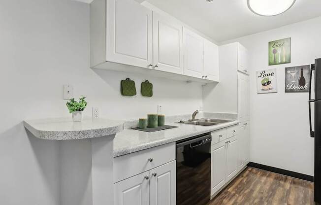 A kitchen with white cabinets and a black refrigerator.