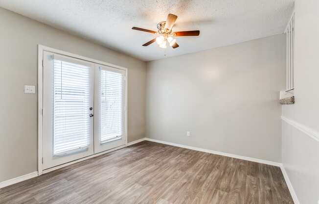 an empty living room with a ceiling fan and a door