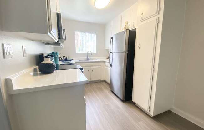 a kitchen with white cabinets and a stainless steel refrigerator