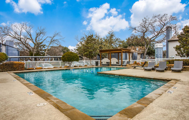 a swimming pool with a gazebo and lounge chairs next to a house