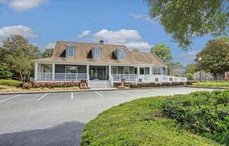 A large house with a porch and a driveway in front.