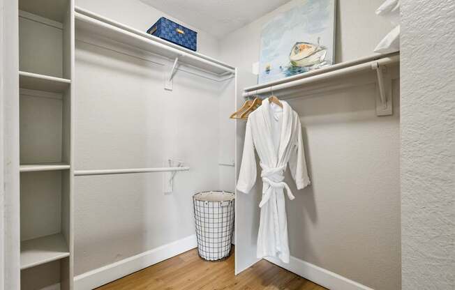 A white robe is hanging on a hanger in a white closet.