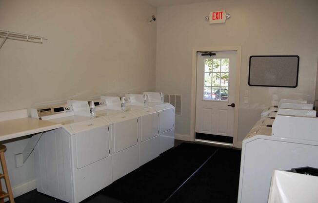 A laundromat with a row of washers and dryers.