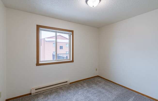 the living room of an empty house with a large window.Fargo, ND Crescent Park Apartments