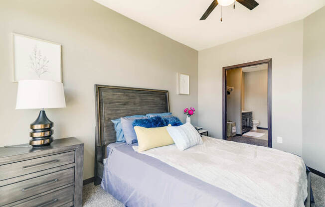 A bedroom with a bed, dresser, and ceiling fan.