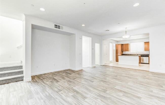 A spacious room with wooden flooring and white walls.