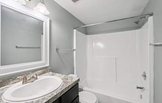 A white bathroom with a sink, toilet, and shower.