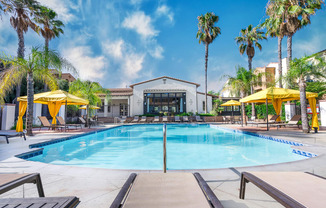 a swimming pool with yellow umbrellas and a white building in the background