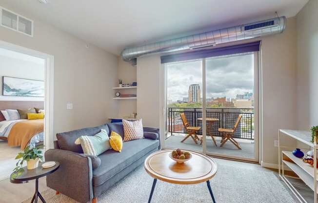 a living area with a couch coffee table and sliding glass door to a balcony