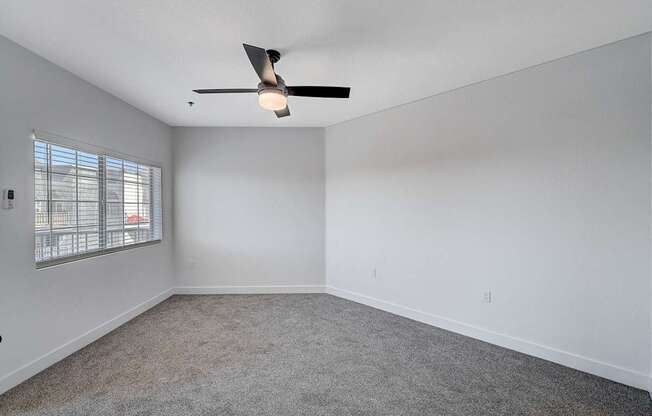 Empty room with a ceiling fan and carpeted floor.